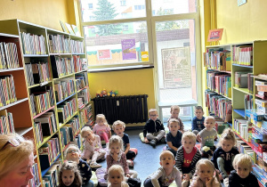 Dzieci słuchają ksiązki czytanej przez panią bibliotekarkę