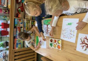 Dzieci malują jesienne drzewa metodą puentylizmu.