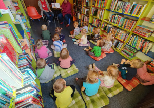 Dzieci słuchają książki czytanej przez panią bibliotekarkę