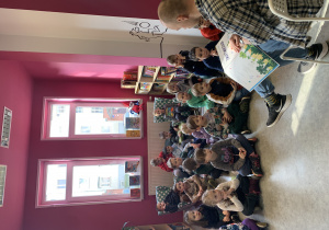 Dzieci słuchają książki pt. "Zmartwiozaur" czytanej przez pracownika biblioteki
