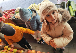 Dzieci wybierają warzywa i owoce na straganie