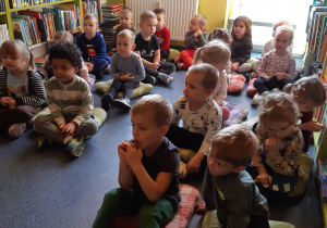 Dzieci słuchają opowiadania czytanego przez panią bibliotekarkę