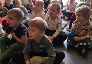 Dzieci słuchają opowiadania czytanego przez panią bibliotekarkę