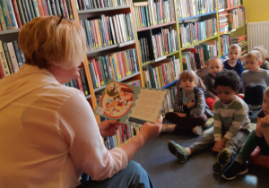Dzieci słuchają opowiadania czytanego przez panią bibliotekarkę