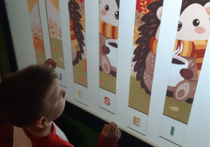 Dziecko układa puzzle na tablicy interaktywnej